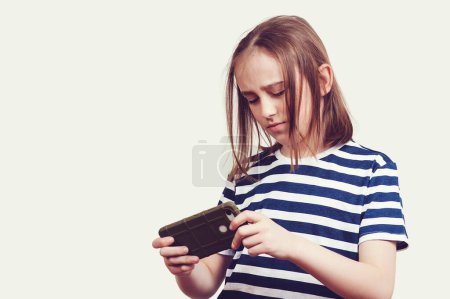 Téléchargez les photos : Triste garçon excité jouant à des jeux sur téléphone mobile. Étudiant avec téléphone portable. Enfant malheureux avec gadget - en image libre de droit