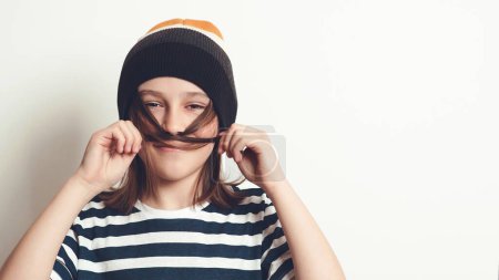 Téléchargez les photos : Garçon excité s'amuser et poser au studio. Portrait d'un garçon de onze ans. Garçon portant un élégant chapeau et un t-shirt en laine. Mode de vie, personnes, concept émotionnel. - en image libre de droit