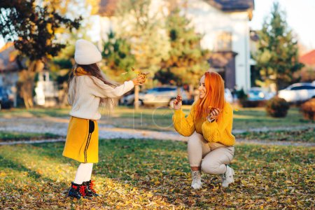 Photo for Happy family enjoying autumn day. Family autumn walk. Autumn holidays, lifestyle, childhood. Mother and child girl throwing leaves in autumn park. - Royalty Free Image