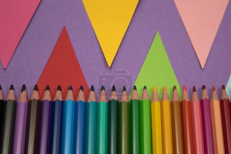 Photo for School or office supplies, row of wooden colored pencils, with purple background with colored triangles vertical photo, with space for text - Royalty Free Image