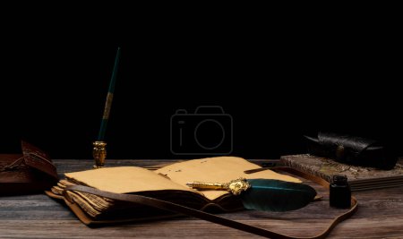 Foto de Diario de hojas de papiro antiguo con pluma y cubierta en relieve con cuaderno de botella de tinta y fondo negro - Imagen libre de derechos