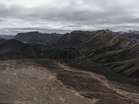 Photo for Aerial shot of Landmannalaugar landscape where we can see different sized and colored mountains in the background and the rest of an volcanic eruption in the foreground where a glacier melted. It leaves these marks in the sand that looks like a lot o - Royalty Free Image