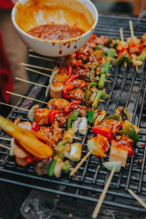 Des tranches de viande juteuses accompagnées de sauce et de légumes sont cuites sur un feu ouvert. Les collations sont cuites sur un gril métallique et prêtes à être servies