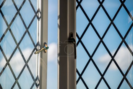 Photo for An open, barred window provides a view of the blue cloudy sky. - Royalty Free Image