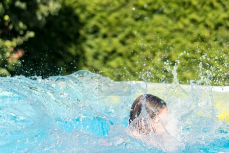 Photo for A girl splashes in the water in her own swimming pool in the garden - Royalty Free Image