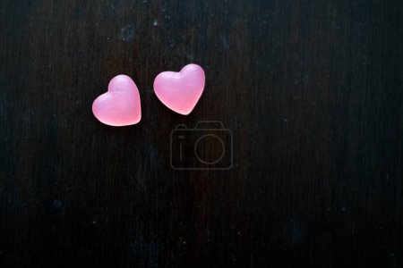 Photo for Two pink wine gum hearts on a dark brown wooden table - Royalty Free Image