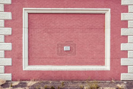 Photo for A sign on a pink brick wall reads "Anti-Graffiti paint has been applied to this asset". - Royalty Free Image