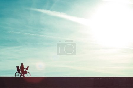 Photo for A mother with child on her bike in strong back light - Royalty Free Image