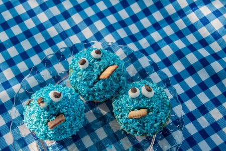 Photo for Blue homemade Cookie Monster muffins stand on a blue checked picnic tablecloth - Royalty Free Image