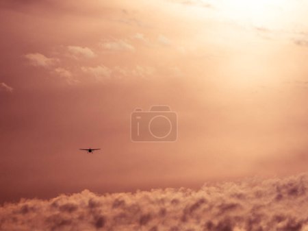 Photo for You see a small aeroplane from behind as it rises into the calm evening sky and flies off into the distance. - Royalty Free Image