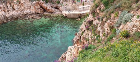 Green slopes under the fortress of the old city above the crystal clear and transparent sea