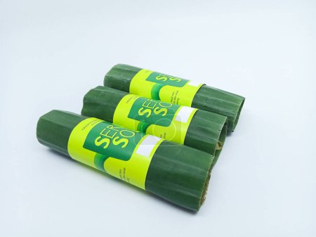 Photo for Surabi solo is a traditional pancake from Indonesia. Sweet food wrapped in banana leaf isolated on the white background - Royalty Free Image