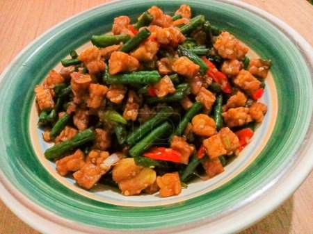 Sauteed Tempe mixed with long beans and soy sauce, it tastes delicious, on the wood table.