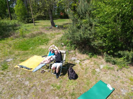 Foto de Un joven con una camisa verde con un colchón al aire libre en medio del bosque. un hombre joven en la hamaca verde - Imagen libre de derechos