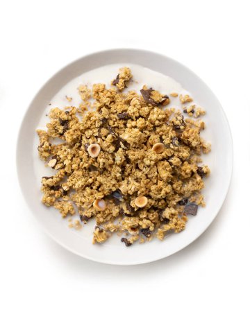 Foto de Tazón de cereales dulces muesli y avellanas, con leche y chocolate, aislado sobre fondo blanco, vista superior - Imagen libre de derechos