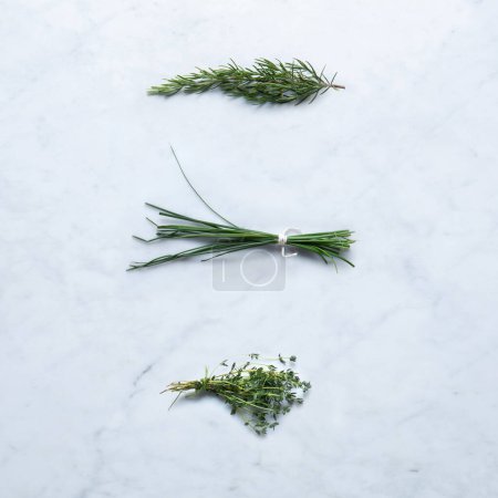 Photo for Aromatic Herbs, Isolated on Marble Background  Bunch of Rosemary Twigs, Chive, Thyme  from Italy, Bundled with Twine on Stone Kitchen Table  Detailed Close-Up Macro, High Resolution, Top View - Royalty Free Image