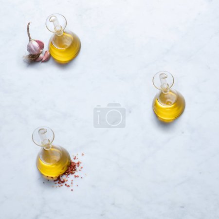 Photo for Ingredients from Italy, Isolated on Marble Background  Extra Virgin Olive Oil in Cruets, Oil Bottles, Crushed Red Hot Chilli Pepper on Stone Kitchen Table  Close-Up Macro, Top View - Royalty Free Image