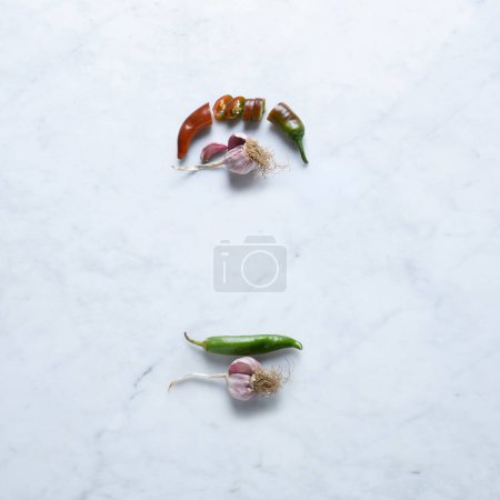 Photo for Garlic and Hot Chilli Pepper, Isolated on Marble Background  Ingredients from Italy, Cut Slices of Peperoncino and Unpeeled Purple Garlic Bulbs on Stone Kitchen Table  Close-Up Macro, Top View - Royalty Free Image