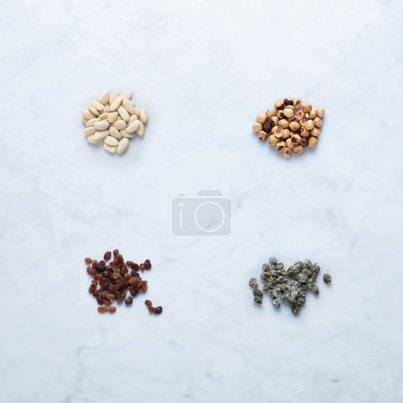 Photo for Ingredients from Italy for Seasoning, Isolated on Marble Background  Heaps of Almond and Hazelnut Peeled Dried Fruit, Raisins, Salted Capers in Bunch  Close-Up Macro, Top View, from Above - Royalty Free Image