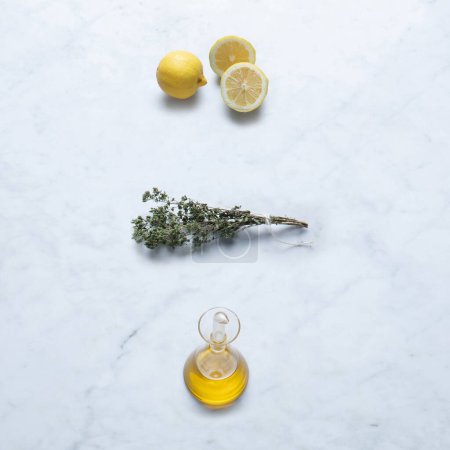 Photo for Ingredients from Italy, Isolated on Marble Background  Cut Slices of Lemon, Extra Virgin Olive Oil in Cruet, Bundled Oregano Twigs with String on Stone Kitchen Table  Close-Up Macro, Top View - Royalty Free Image