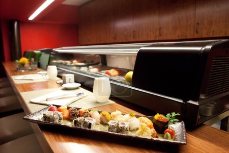 Téléchargez les photos : Sushi en japonais Restauration Cuisine Machine Flou fond, Assiette avec sauce soja, Rangée de Nigiri et rouleaux avec Wasabi, Caviar rouge, Dîner gastronomique sur napperons Haute Résolution Fermer - en image libre de droit