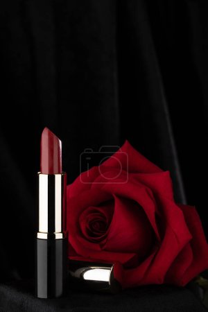 Foto de Rosa roja y lápiz labial sobre fondo negro brillante maquillaje cosmético, colores oscuros y detalles de macro, símbolo de la pasión icónica de alta resolución de cerca - Imagen libre de derechos