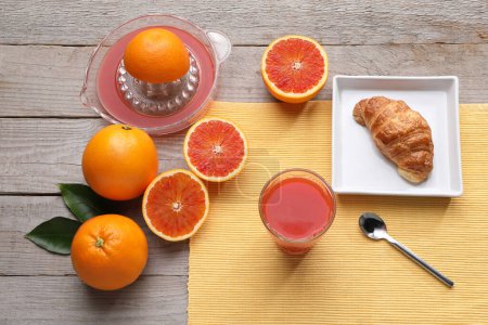 Foto de Desayuno con zumo de naranja en una mesa de madera blanca naranjas enteras, hojas verdes, con sombras, jugo rojo Ingrediente minimalista de alta calidad Foto - Imagen libre de derechos