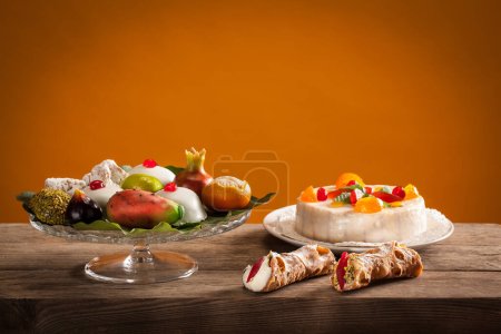 Photo for Typical Sicilian sweets, ricotta cannoli, Sicilian cassata cake, almond pastries, and marzipan fruit - Royalty Free Image