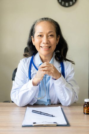 Foto de Médico asiático senior, psiquiatra, médico femenino consultando a paciente joven, usando estetoscopio para escuchar, cita clínica, hospital. - Imagen libre de derechos