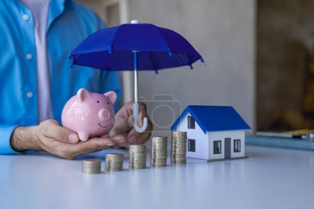Foto de Concepto de seguro y salud, familia y propiedad, hombre con paraguas en los agentes de seguros presentan juguetes que simbolizan la protección. - Imagen libre de derechos