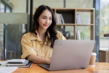 Téléchargez les photos : Femme asiatique travaillant avec des documents financiers et ordinateur portable au bureau, concept de comptabilité financière - en image libre de droit