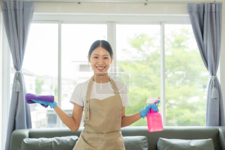 Téléchargez les photos : Jeune femme asiatique appréciant le nettoyage de printemps dans la maison ou l'appartement, les travaux ménagers et le concept d'entretien ménager - Heureuse femme asiatique ou femme au foyer avec une serpillière nettoyant la maison. - en image libre de droit