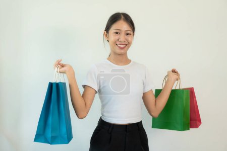 Foto de Mujer asiática joven sonriendo y levantando los brazos sosteniendo bolsas de compras, aislada sobre fondo blanco, concepto de comprador - Imagen libre de derechos