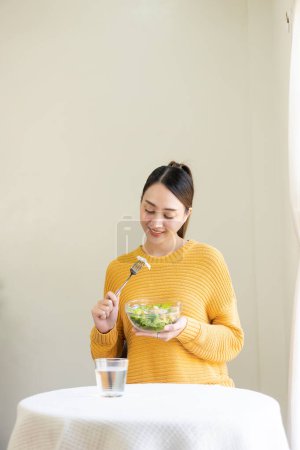 Photo for Beautiful Asian woman eating salad with a big smile Happy smiling face Healthy diet concept Her face and skin are healthy, fresh and bright. - Royalty Free Image