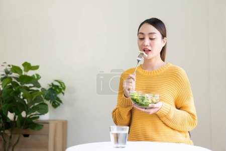 Photo for Beautiful Asian woman eating salad with a big smile Happy smiling face Healthy diet concept Her face and skin are healthy, fresh and bright. - Royalty Free Image