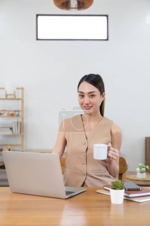 Téléchargez les photos : Femme d'affaires souriante travaillant dans le bureau à domicile avec ordinateur portable et tablette, femme asiatique heureuse Fille avec appareil numérique interagissant avec les clients, espace de copie de bannière - en image libre de droit