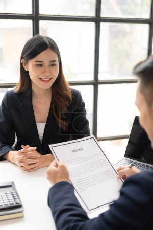 Photo for Young Asian woman is interviewing for a job in the office. Focus on tips for writing a resume Employers are checking good CVs of applicants with prepared skills. Brokers are considering - Royalty Free Image