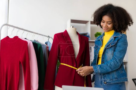 Foto de Chica afroamericana presenta y vende ropa en línea a través de transmisión en vivo en Internet, elige una tienda de ropa con estilo. Diseñadores de moda dibujan imágenes de nuevas colecciones. - Imagen libre de derechos