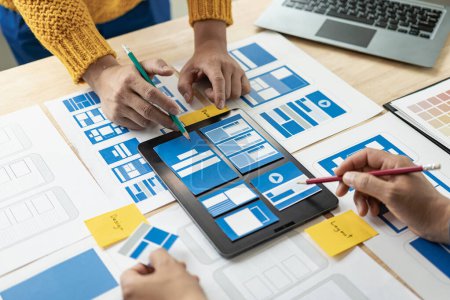 Photo for A team of UI UX web designers is working together to develop a mobile responsive website by previewing UI UX Front End Designer website development ideas. - Royalty Free Image