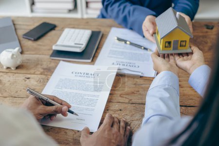 Photo for A real estate agent discusses the terms of a home purchase contract and asks the client to sign the documents to legally enter into a contract. Selling a home. Close-up photo. - Royalty Free Image