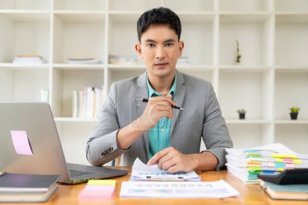 Foto de Asiático hombre de negocios que trabaja en la oficina con el ordenador portátil y los documentos sobre la mesa Trabajo en el lugar de trabajo, documentos comerciales, conceptos de planificación financiera - Imagen libre de derechos