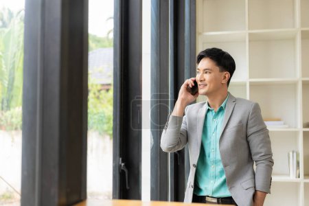 Téléchargez les photos : Homme d'affaires asiatique utilisant un smartphone et travaillant au bureau à l'aide d'un ordinateur portable et parlant sur téléphone mobile, concept d'entreprise financière - en image libre de droit