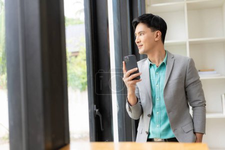 Téléchargez les photos : Homme d'affaires asiatique utilisant un smartphone et travaillant au bureau à l'aide d'un ordinateur portable et parlant sur téléphone mobile, concept d'entreprise financière - en image libre de droit