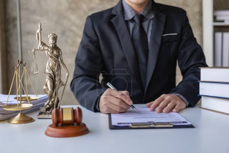 Téléchargez les photos : Asiatique avocat masculin travaillant dans un cabinet d'avocats avec un marteau de juge et une échelle de poids sur la table, concept de consultation juridique. - en image libre de droit