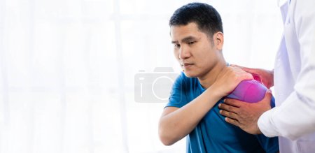 Téléchargez les photos : Jeune homme asiatique faisant de la physiothérapie et demandant conseil de douleurs musculaires avec épaule, membres dans le centre de réadaptation. - en image libre de droit