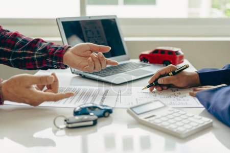 Photo for Car loan with calculator Explain in detail to customers the terms and conditions in the distributor office. Provide financial and insurance services Close-up pictures - Royalty Free Image