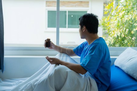 Téléchargez les photos : Patient masculin se reposant sur un lit d'hôpital La dépression est liée à l'absence d'esprit. Anxiété et stress Du seul patient asiatique dans un lit d'hôpital. - en image libre de droit