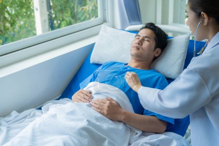 Téléchargez les photos : Patient asiatique de sexe masculin couché sur le lit avec une équipe de médecins fournissant consultation et soulagement à côté du concept de santé médicale. - en image libre de droit