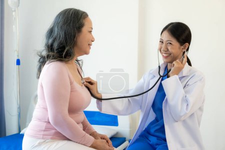 Téléchargez les photos : Femme asiatique médecin parle au patient avec le sourire pour encourager le patient à l'hôpital Une femme asiatique âgée rend visite à un médecin dans un bureau de l'hôpital. Parlez des résultats de l'examen de santé - en image libre de droit