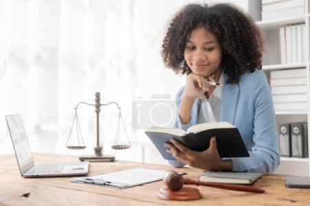 Photo for Attractive young African American lawyer working in the office with contract and legal documents when sitting at the table. Law, legal services, advice, justice. - Royalty Free Image